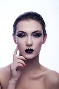 woman wearing black lipstick, black eyeshadow, and black mascara posing in front of white background thumbnail