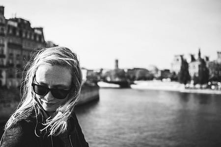 woman in sunglasses near body of water grayscale photo thumbnail