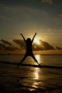 silhouette of person jumping on seashore during sunrise thumbnail