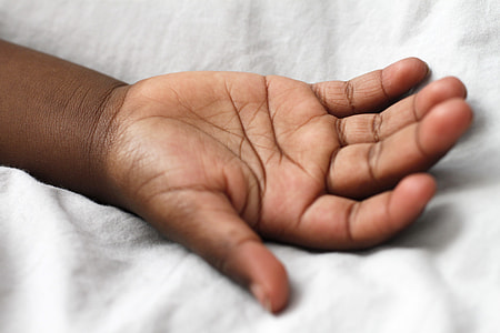 person's empty hand on white sheets thumbnail