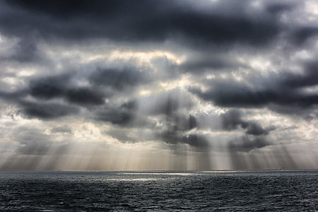 photography of sun raise over cloudy sky and body of water thumbnail