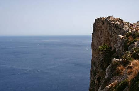 mountain cliff near sea under cloudy sky thumbnail