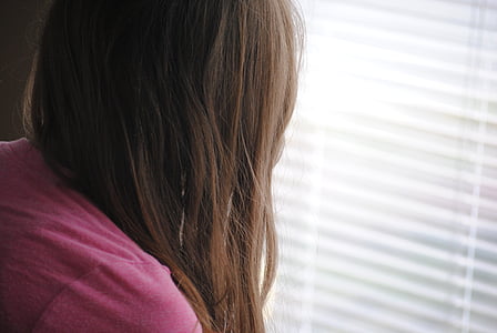 photo of woman wearing pink top facing white window blind thumbnail