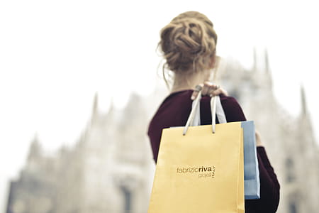 A young blond woman wearing a red velvet dress holding shopping bags in her hand on her shoulder thumbnail