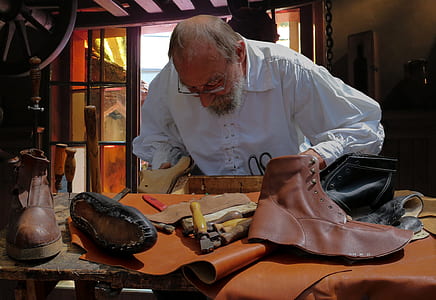 man making leather boots inside house thumbnail