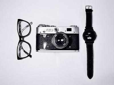 gray and black MILC camera beside watch and eyeglasses on white background thumbnail