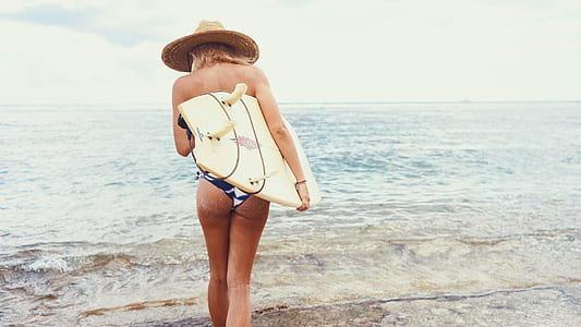 woman carrying surfboard walking towards the sea thumbnail