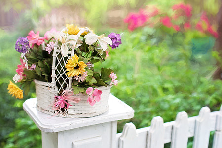 woven white basket with flower arrangement on fence thumbnail