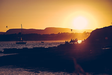 silhouette photography of people sitting on bench looking at beach thumbnail