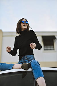 woman wearing turtle neck sweater sitting on vehicle roof thumbnail