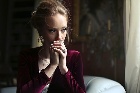 A young blonde woman wearing a red velvet dress sitting on the white couch thumbnail