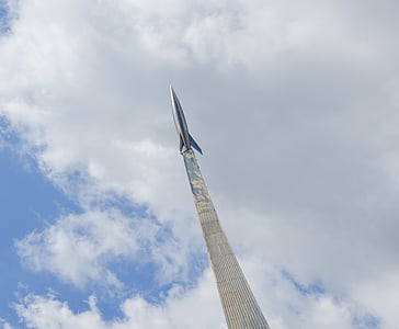 gray stainless steel rocket on top of gray high-rise building under cloudy sky thumbnail
