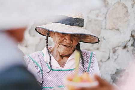 woman wearing brown sun hat standing near gray concrete wall thumbnail