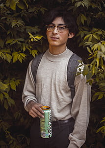 man wearing gray sweater holding green can thumbnail