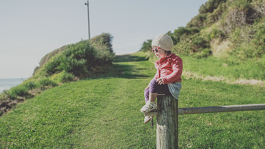 children wearing red jacket sitting near green grass during daytime thumbnail