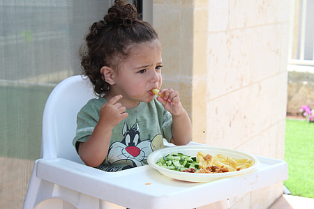 girl in green t-shirt sitting on floor chair eating fruit slice thumbnail