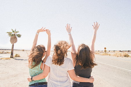 three women looking standing right next to each other in front of green tree during daytime thumbnail