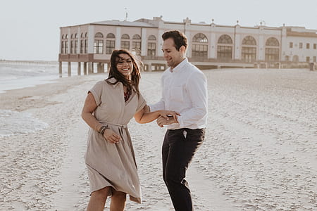 man holding a girl at the seashore near brown building thumbnail