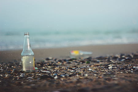 tilt shift lens photography of bottle on seashore thumbnail