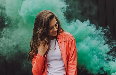 woman smiling while holding hair standing near green smoke thumbnail