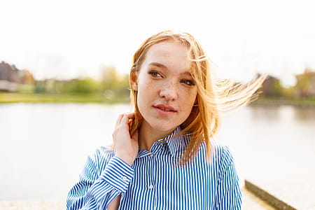 Photography of Woman Near Lake Touching Neck With Right Hand thumbnail