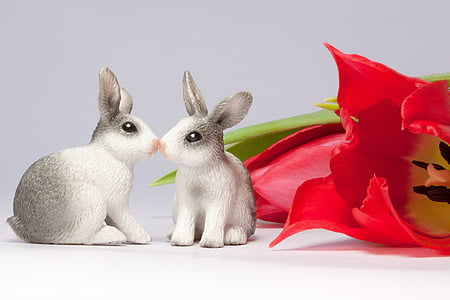 two white-and-gray ceramic bunny figurines beside red tulip thumbnail