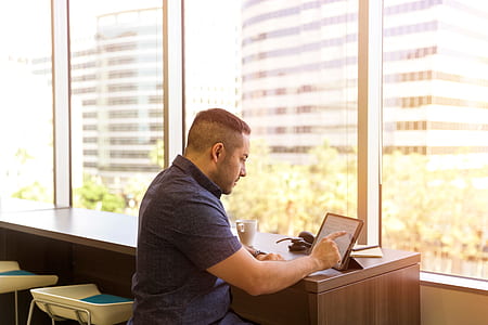 man sitting in front of table while using tablet during daytime thumbnail