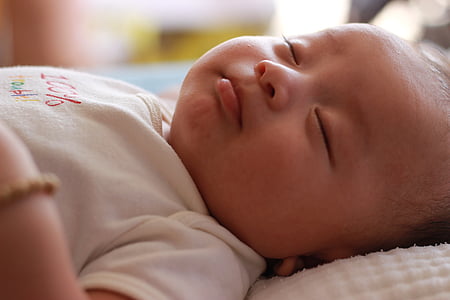 baby lying on white mat while sleeping photo thumbnail