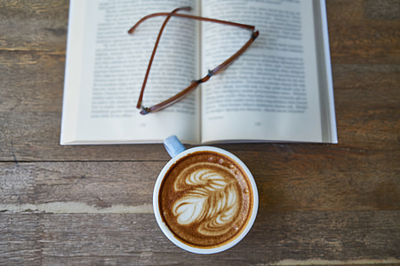 white ceramic mug filled with coffee latte beside brown framed eyeglasses on book thumbnail