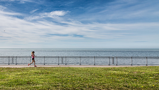 woman running near body of water at the shore during daytime thumbnail