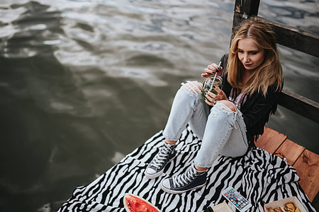 Blonde woman having a healthy snack at the wooden pier thumbnail
