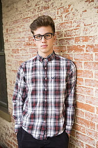 Man In Red And White Plaid Dress Shirt And Black Bottoms With Black Frame Eyeglasses thumbnail