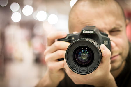 shallow focus photography of man holding DSLR camera thumbnail