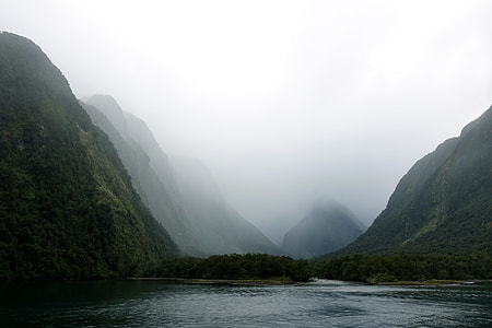 body of the water surrounded by green mountain and fogs thumbnail