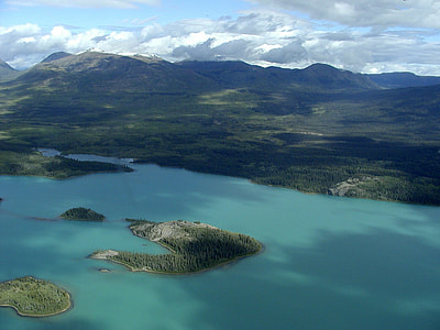 aerial photography of ocean near mountain under blue and cloudy sky during daytime thumbnail