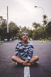 man in gray and black camouflage sweatshirt sitting on road thumbnail