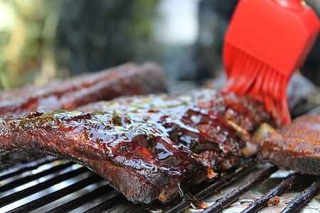 person brushing grilled meat close-up photo thumbnail