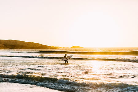 person holding white surfboard on body of water thumbnail