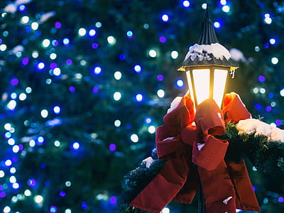 shallow focus photography of lamp post with red ribbon and green garland thumbnail
