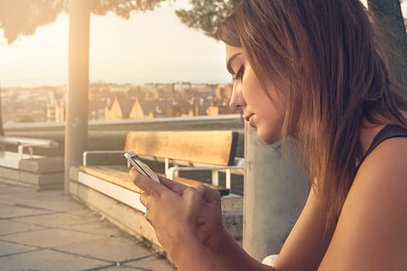 woman wearing black top holding smartphone near bench thumbnail