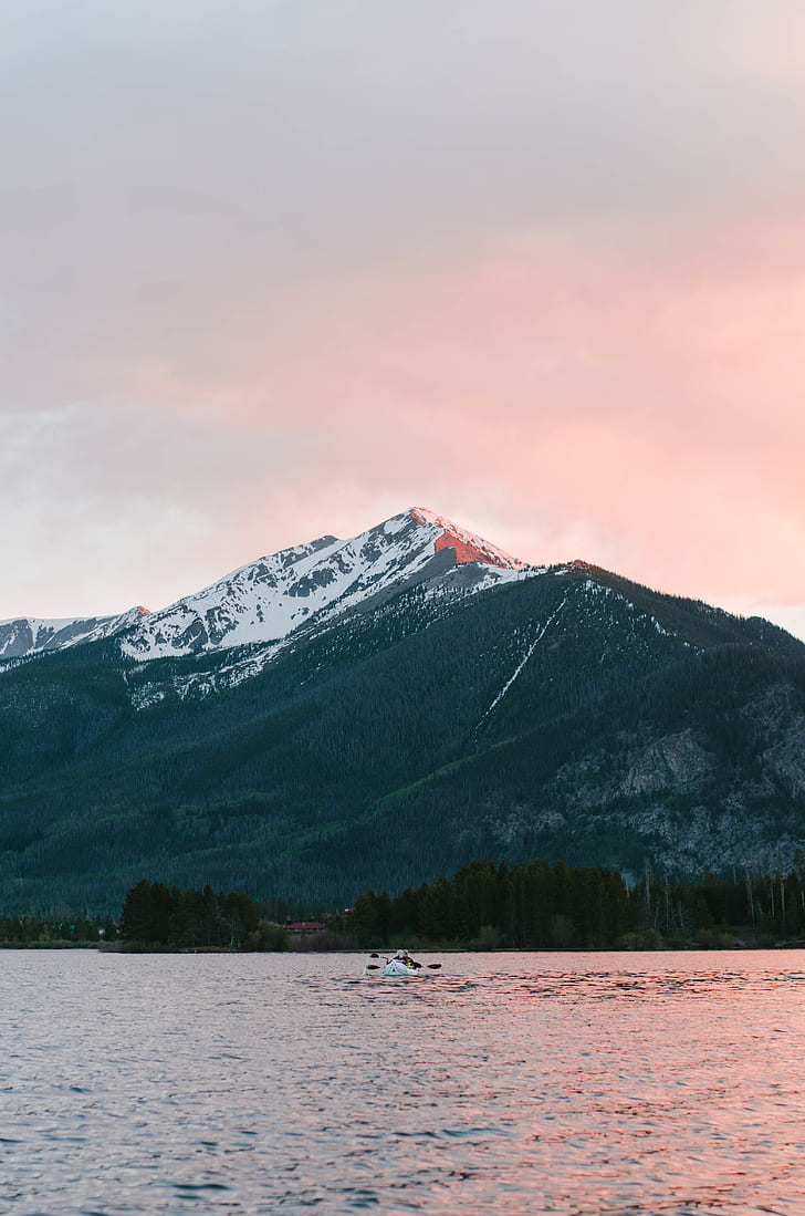 person kayaking on sea under nimbus clouds