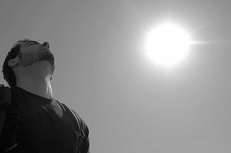 grayscale photo of man wearing t-shirt carrying backpack under sun thumbnail
