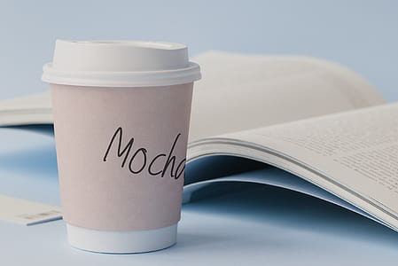 white disposable cup near book thumbnail