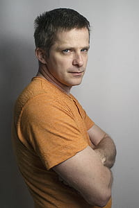 man in orange shirt hands crossed on his chest thumbnail