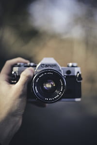 person holding of black and gray Canon DSLR camera thumbnail