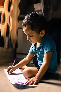 boy holding ballpen while writing in paper thumbnail