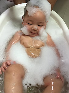 baby lying on bathtub covered with bubbles thumbnail
