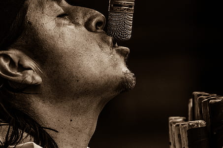 close-up photography of man kissing gray microphone thumbnail