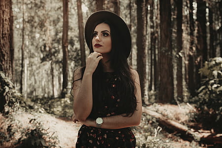woman wearing black hat looking up in the middle of forest thumbnail