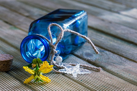 blue translucent bottle with yellow petaled flower thumbnail